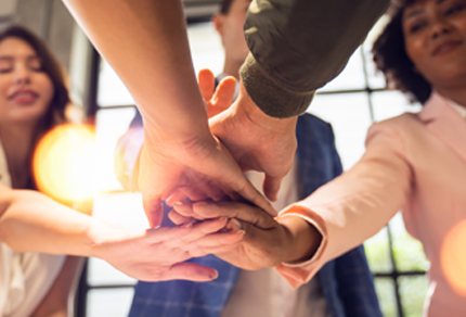 Close-up of a diverse group of people stacking their hands together in a gesture of teamwork and unity.