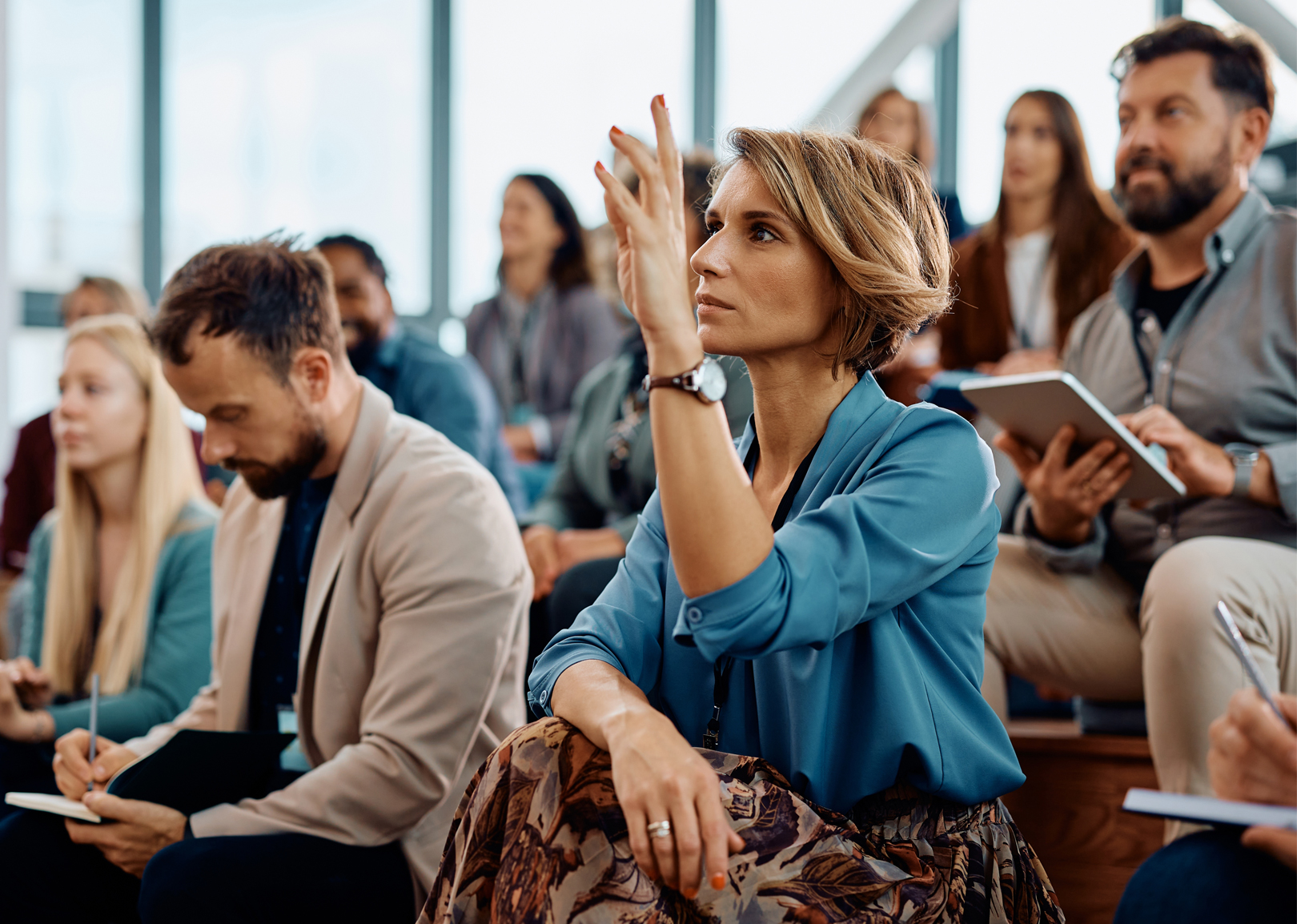 In a large audience, a female raises her hand